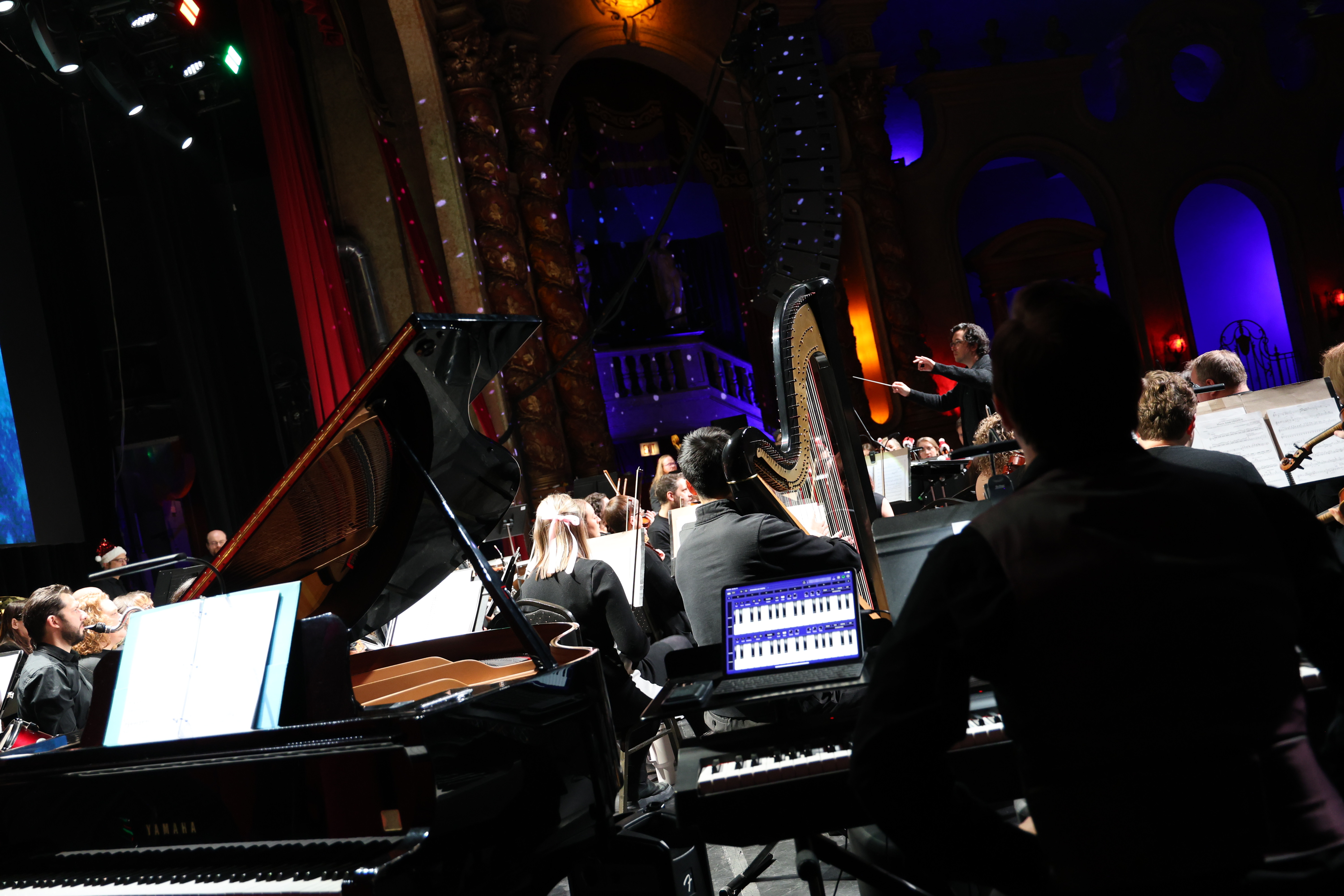 Orchestra performing on stage with conductor and instruments.